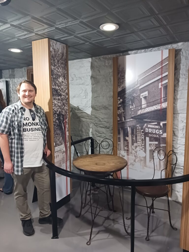 A man standing next to a table from Robinson's Drug Store, where the plans for the Scopes Trial were initially hatched by Dayton's leaders.