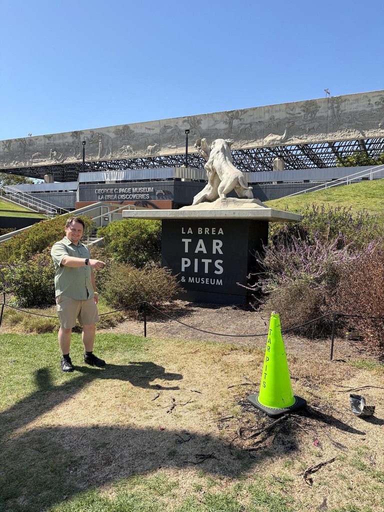 A person pointing to asphalt seeping up out of the ground inside Hancock Park, the site of the famous La Brea Tar Pits & Museum.